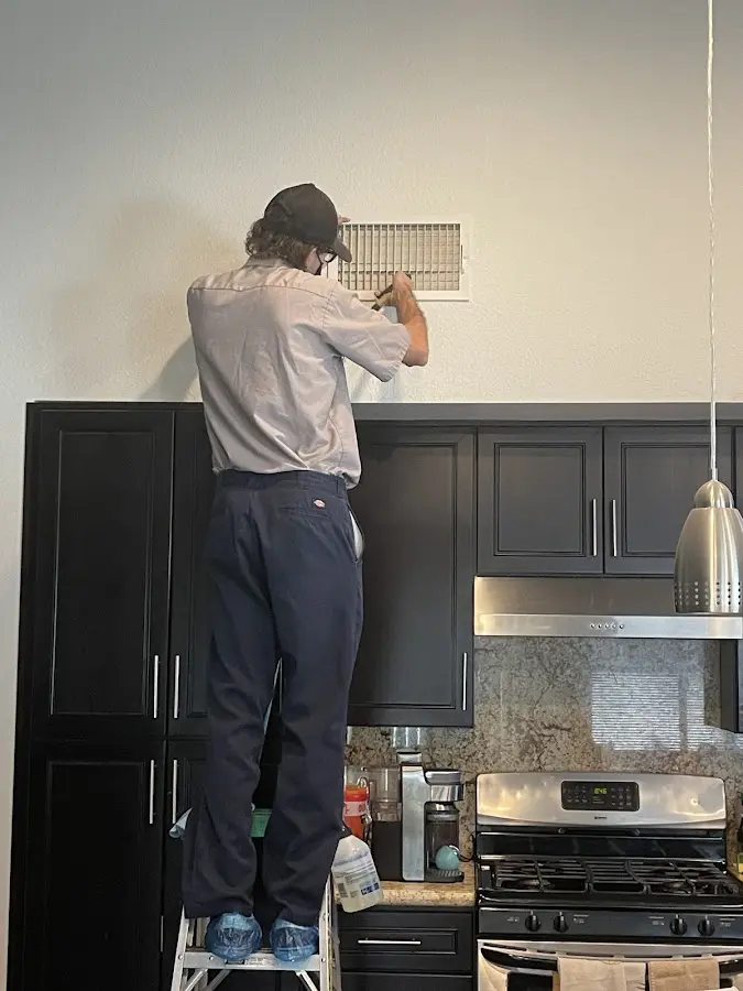Technician inspecting an air vent during HVAC service in Atlantic
